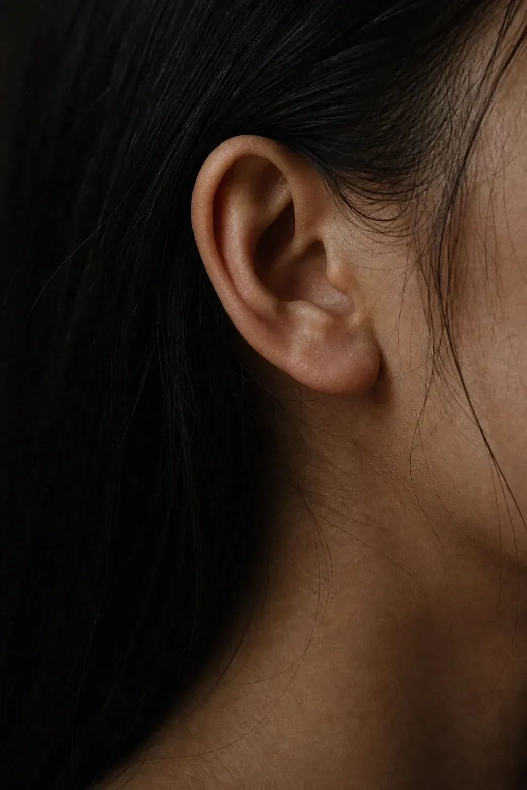 An ear and neck framed by dark hair.