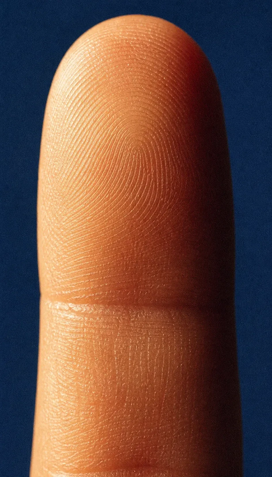 Close-up of a fingertip against a deep blue background.